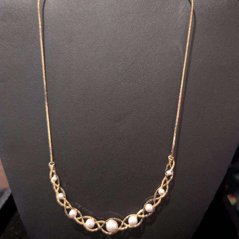 gold-tone necklace with white, round pearls set in a twisted bar design.